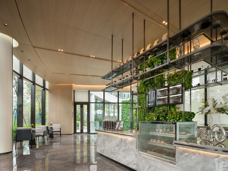 Contemporary cafe design featuring green accent walls and ample natural light through large windows.